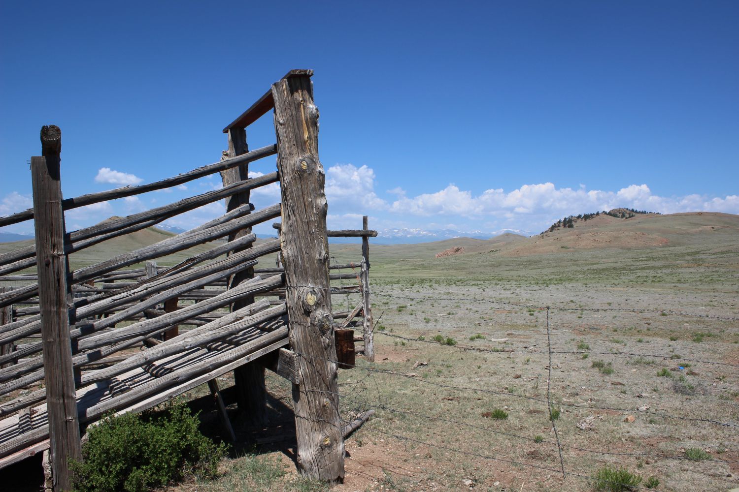 Benefits to Park County represented by grasslands with a wooden cattle chute and wire fence.